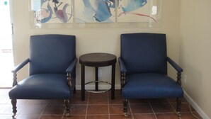 Two blue armchairs with wooden legs, a small round table, and abstract art on the wall. - Holiday House Motel (Lake Worth)