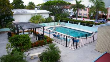 A rooftop pool with a pergola, lounge chairs, and a barbecue area.