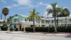 A motel with a green building and a covered parking area. - Holiday House Motel (Lake Worth)