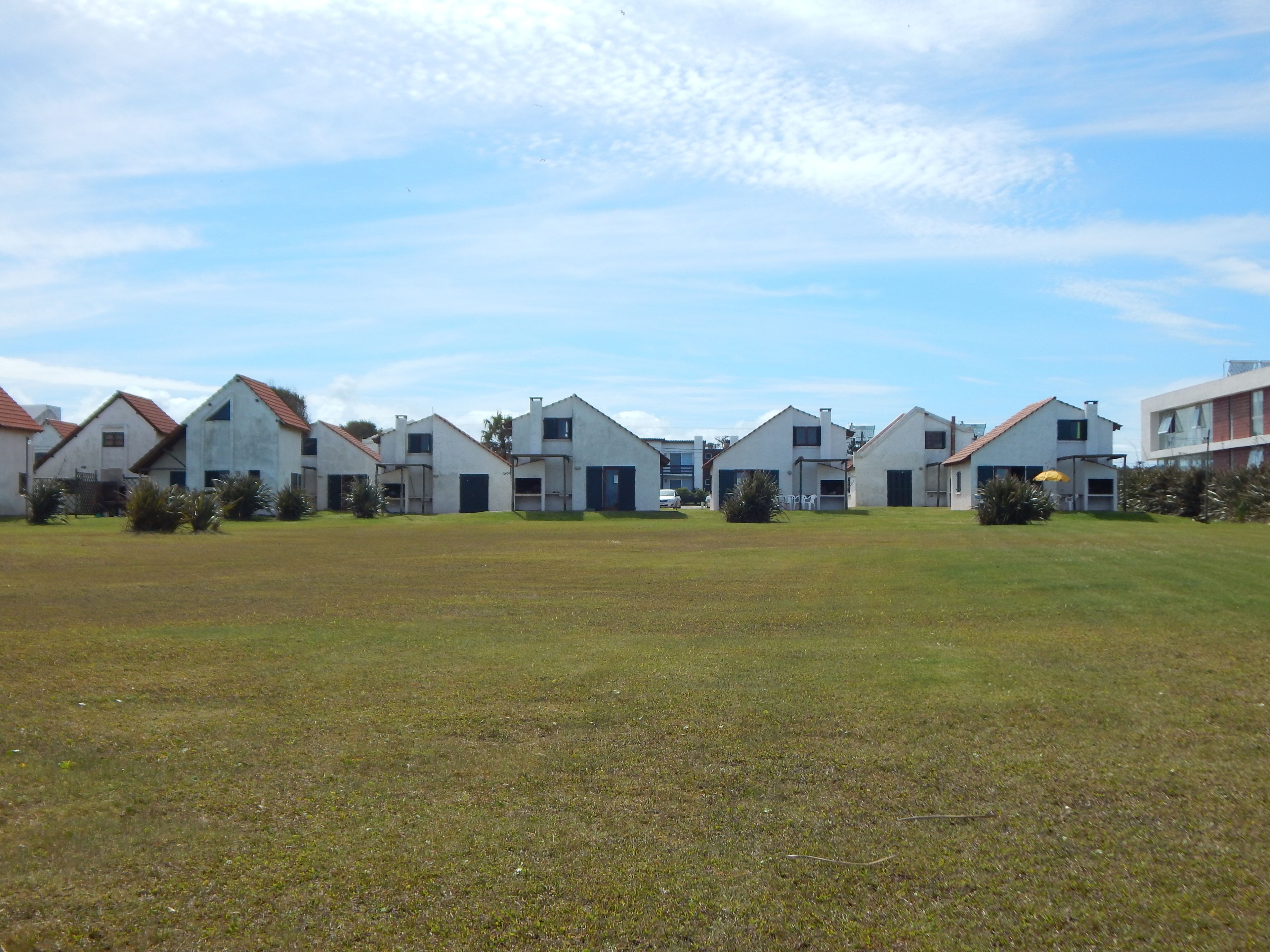 A row of modern houses with a grassy lawn in front.