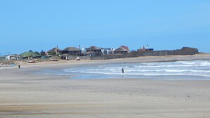 Une plage avec des maisons et un phare en arrière-plan.