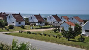 Une rangée de maisons blanches aux toits rouges, un ciel dégagé et l’océan en arrière-plan.