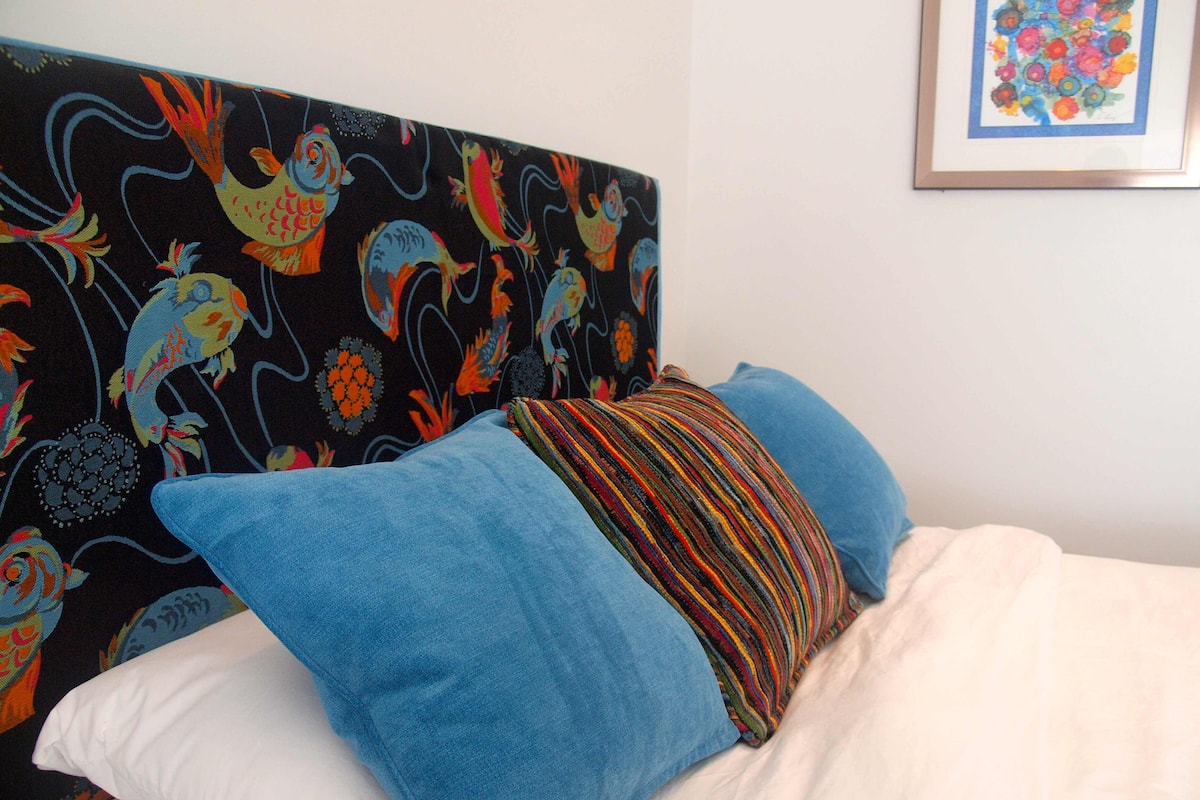 Un lit avec une tête de lit colorée et des oreillers bleus.
