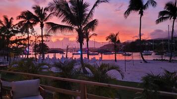 Enjoy the tranquil beachfront view from this balcony, overlooking the marina and palm trees.