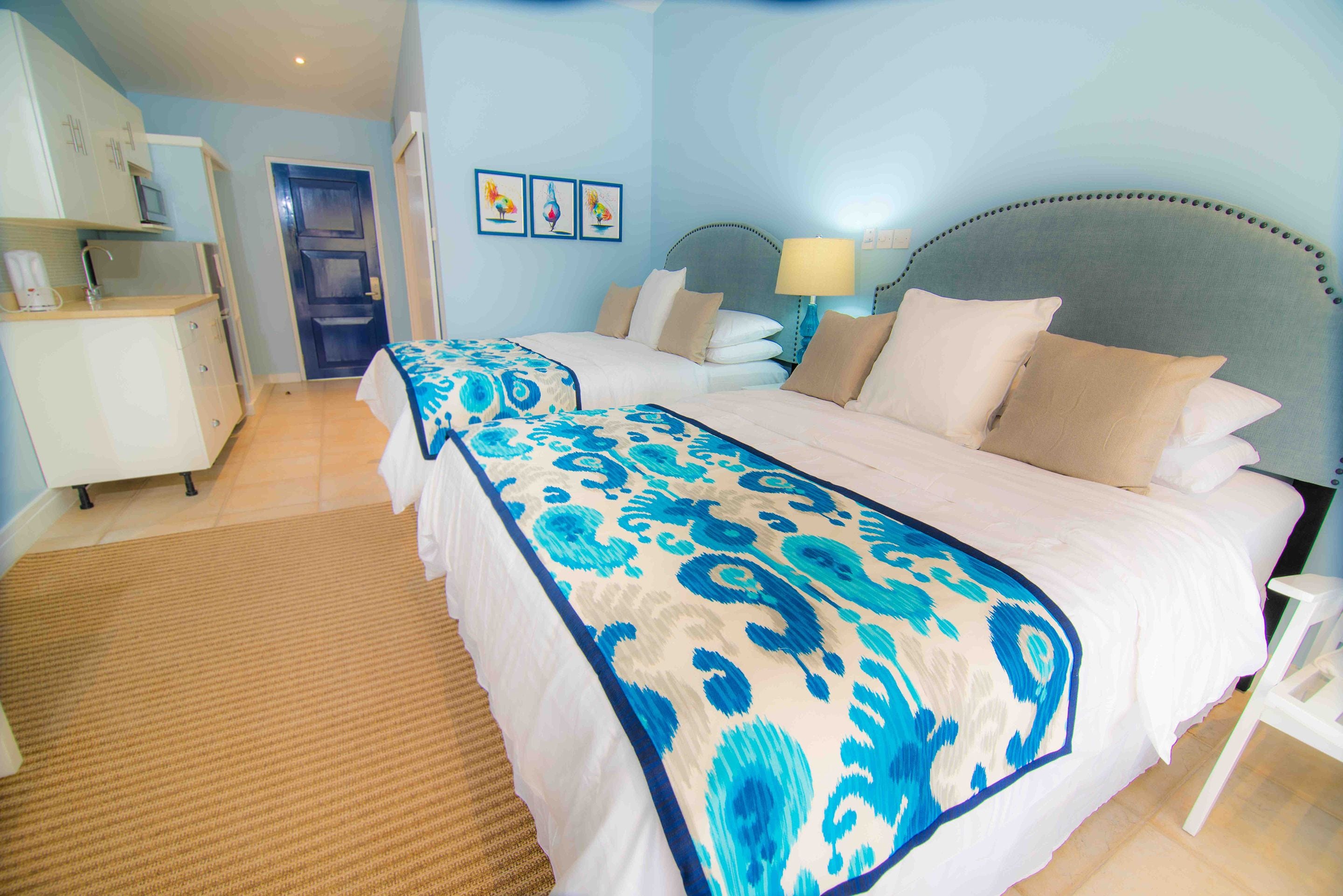A hotel room with a large bed, a bedside table, a lamp, and a door leading to the bathroom.