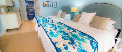 A hotel room with a large bed, a bedside table, a lamp, and a door leading to the bathroom.