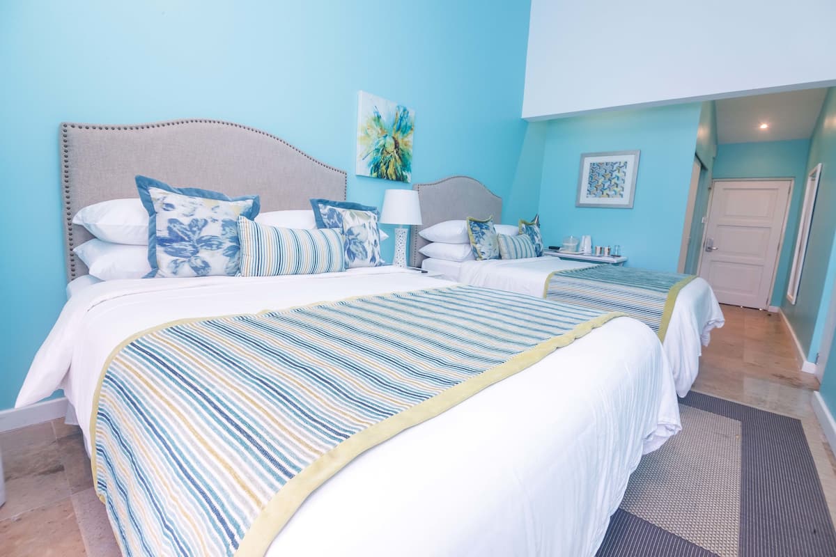 Une chambre d’hôtel avec deux lits, une grande fenêtre et une porte.