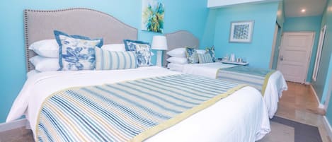 A hotel room with two beds, a large window, and a door.