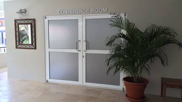 A conference room with a frosted glass door, a potted plant, and a wooden bench.