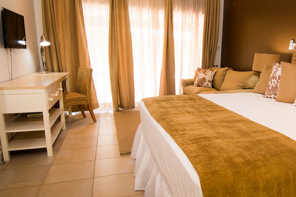 Une chambre d’hôtel avec un grand lit, un bureau, une chaise et un téléviseur fixé au mur.