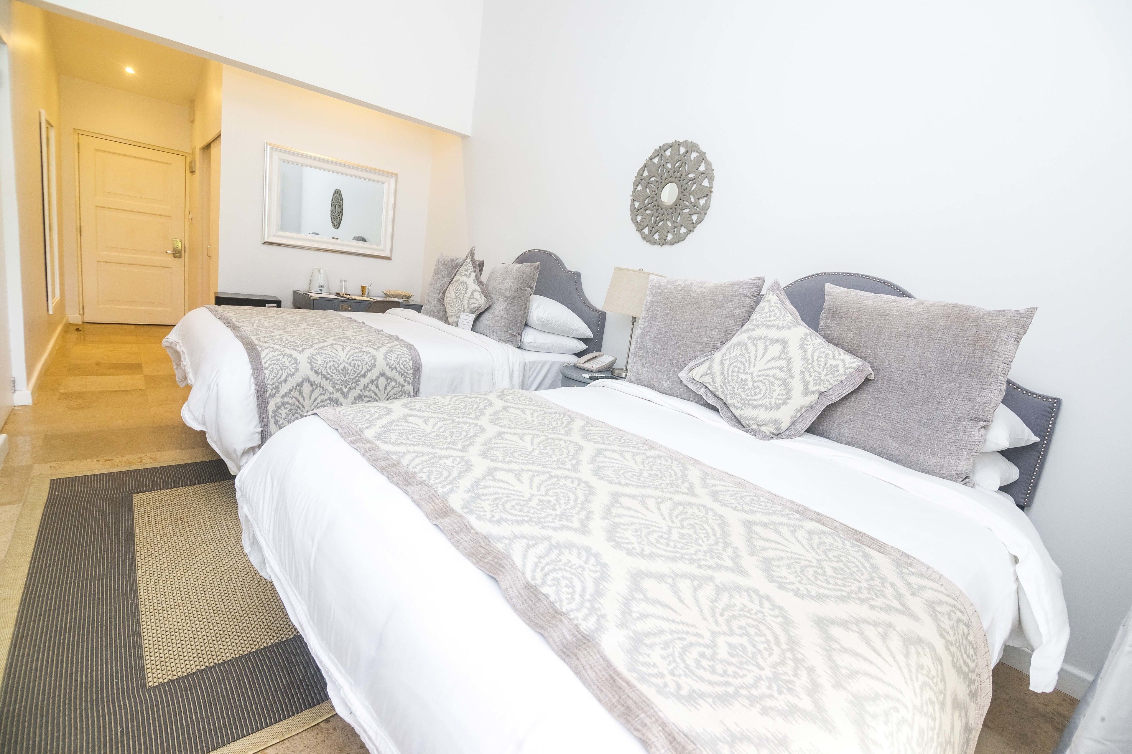 A hotel room with two beds, a large mirror, and a door leading to a hallway.