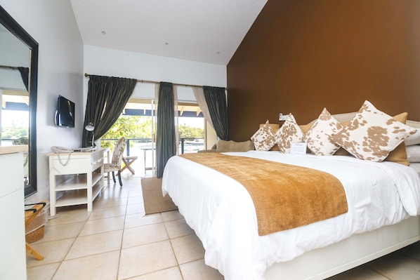 A modern hotel room with a large bed, a desk with a chair, a television, and a view of the outdoors. - Blue Lagoon Hotel & Marina (Ratho Mill)