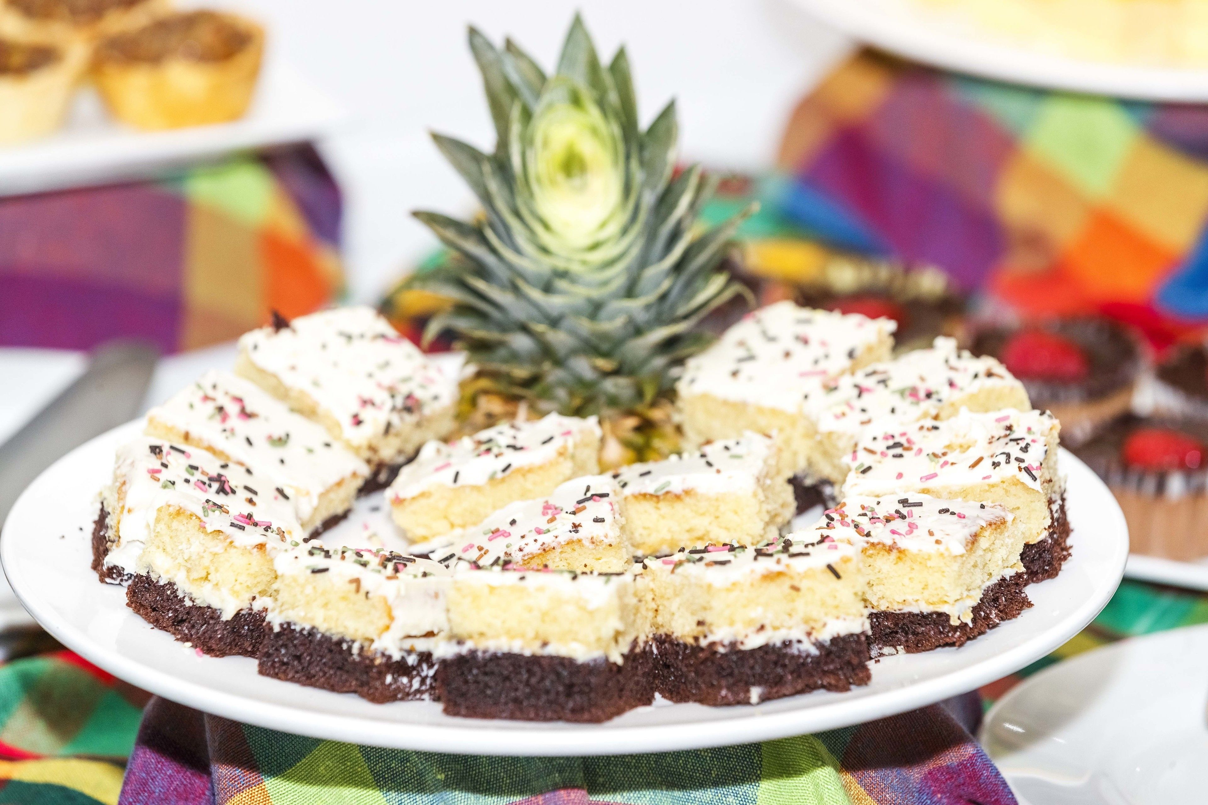 A round cake with white frosting and sprinkles on a white plate.