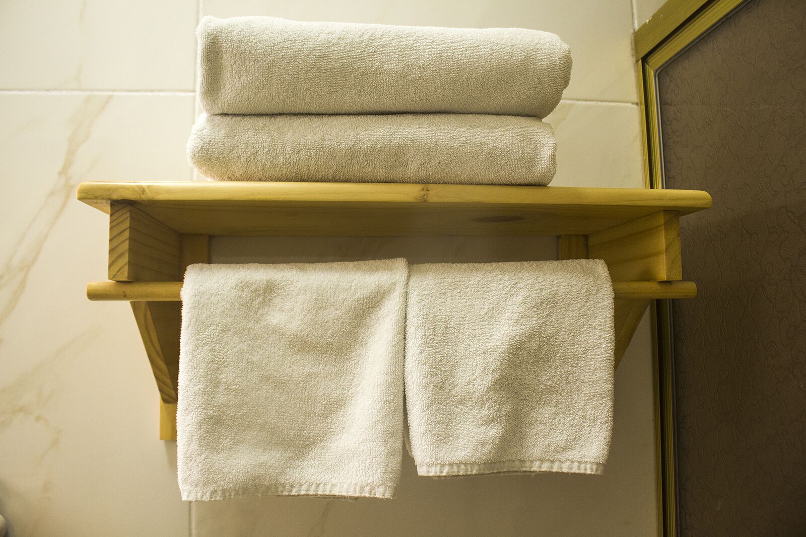 A bathroom with a wooden towel rack holding three folded towels.