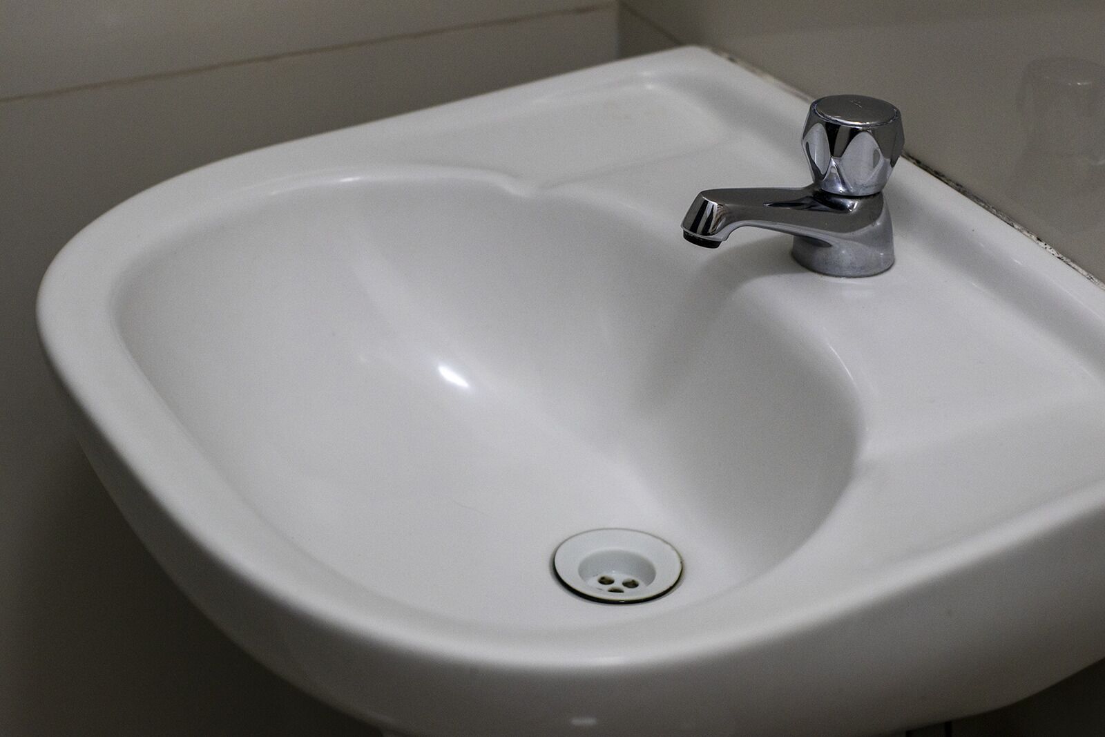 A white pedestal sink with a chrome faucet and a single drain hole.