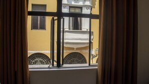A window with a view of a yellow building with white trim and a balcony. - Plaza Mayor Lima (Lima)
