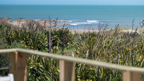 Vista de playa con una mesa y sillas al frente.