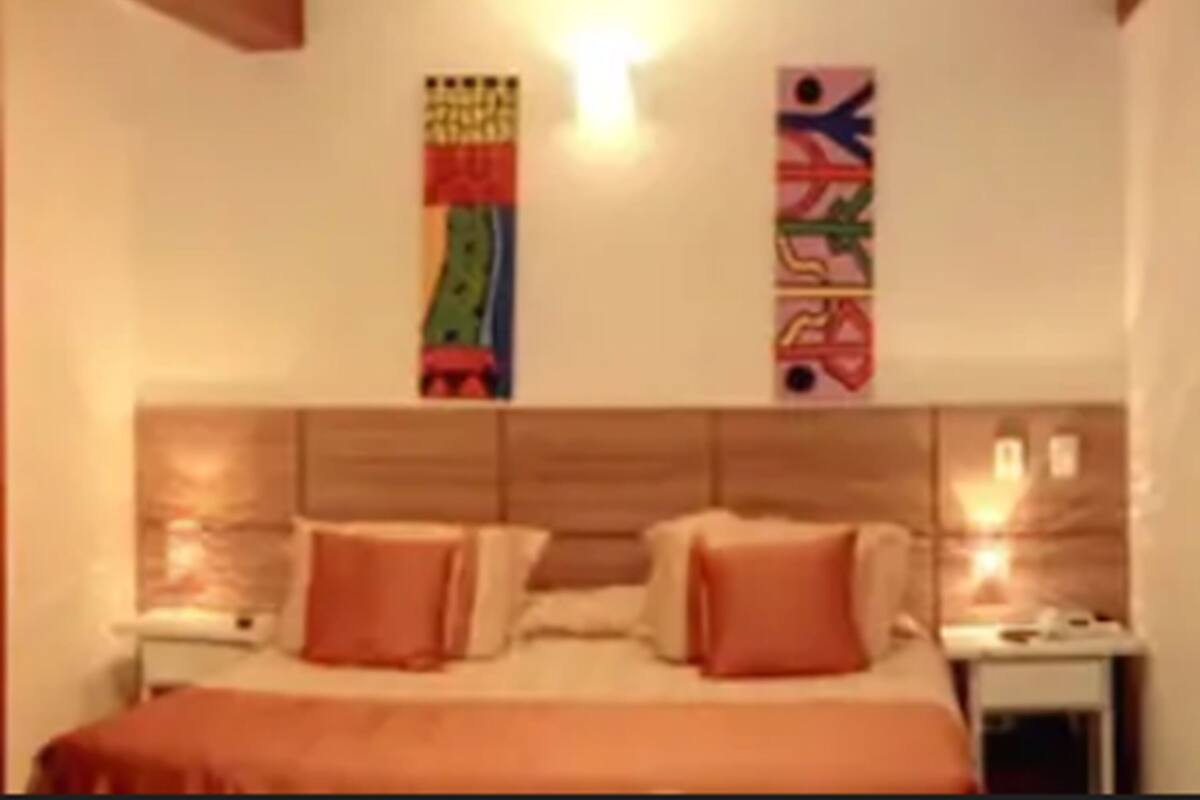 Une chambre d’hôtel comprenant un lit, deux tables de chevet et une tête de lit ornée d’un panneau en bois.