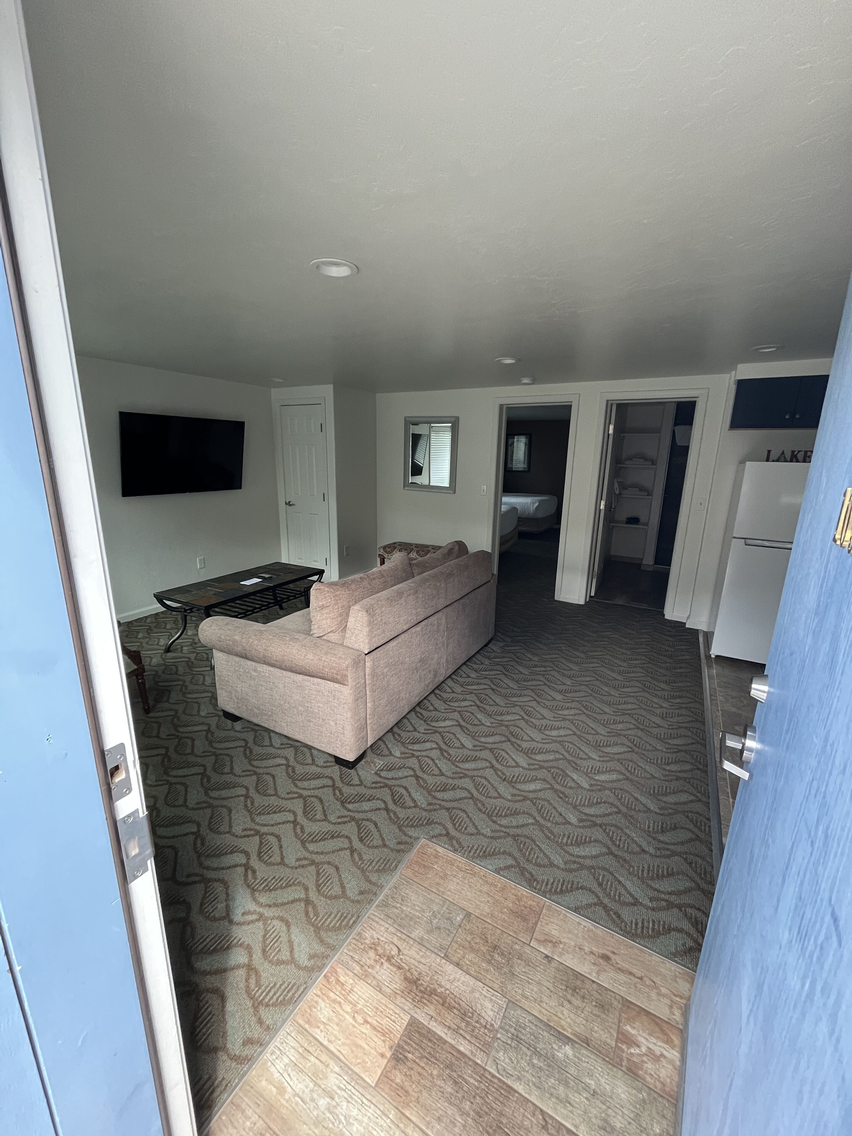 A living room with a sofa, a flat-screen TV, and a patterned carpet.