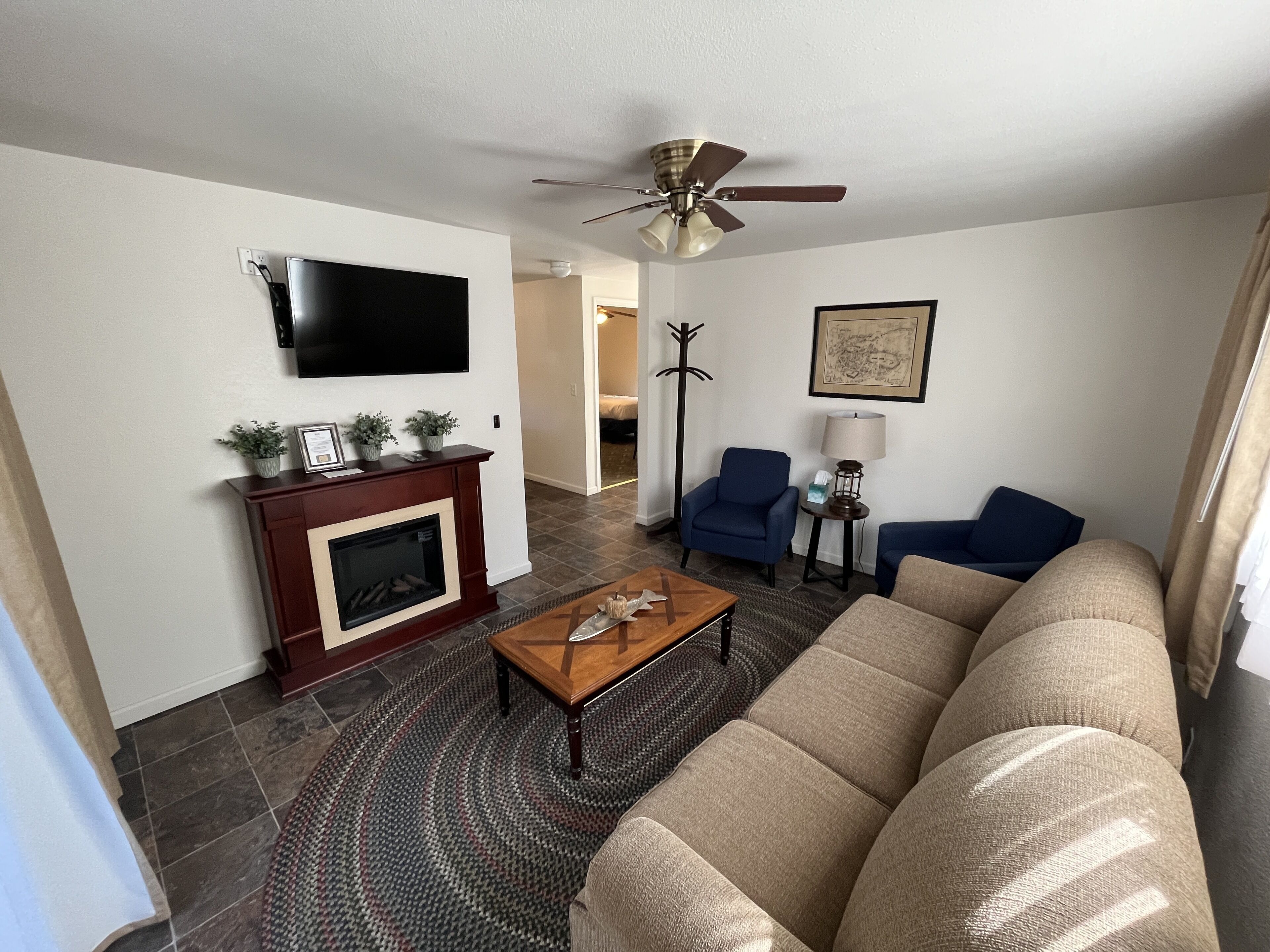 A living room with a fireplace, a ceiling fan, a television, and a sofa.