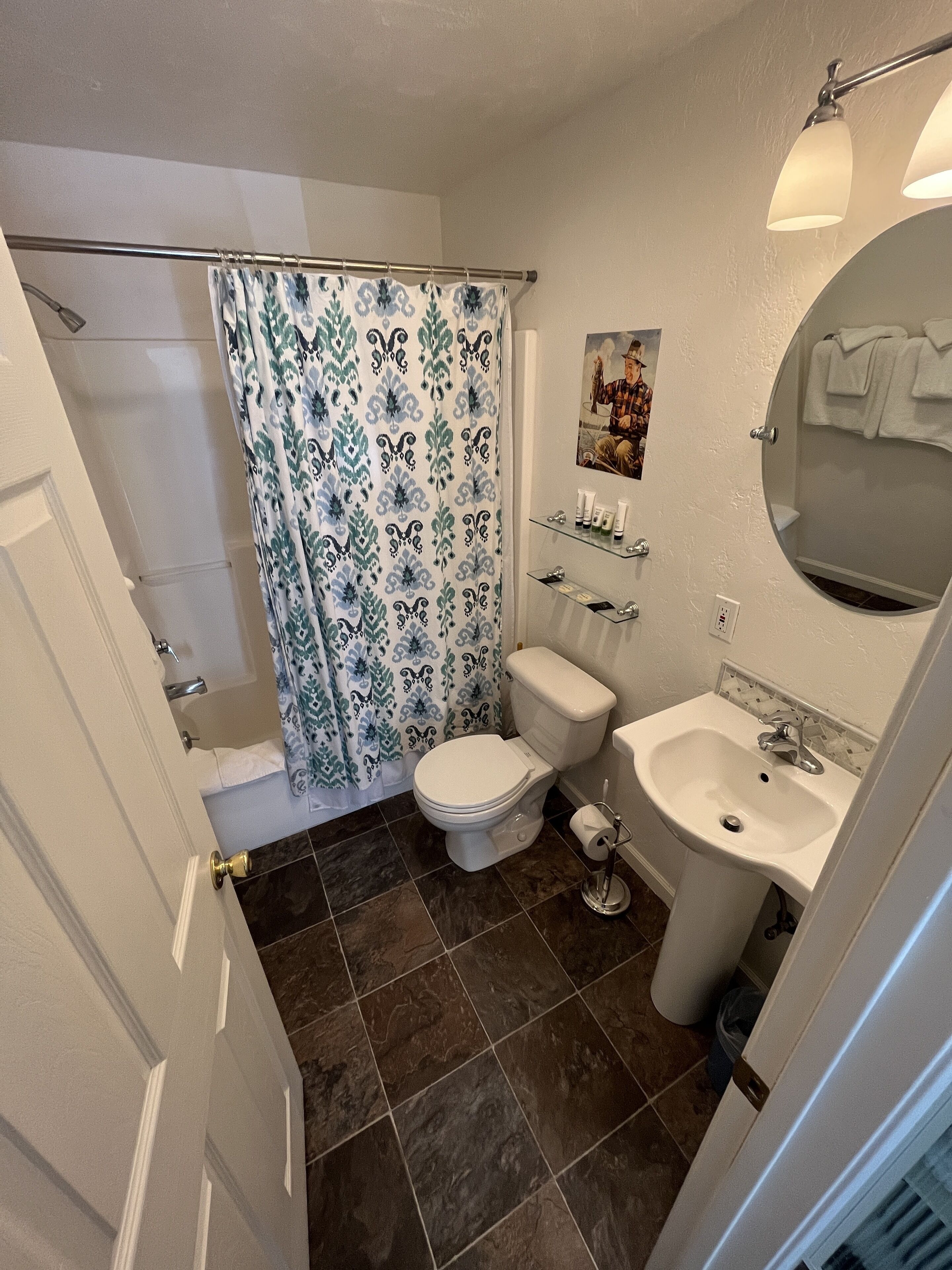 Une salle de bain équipée de toilettes, d’un lavabo, d’un rideau de douche et d’un miroir.