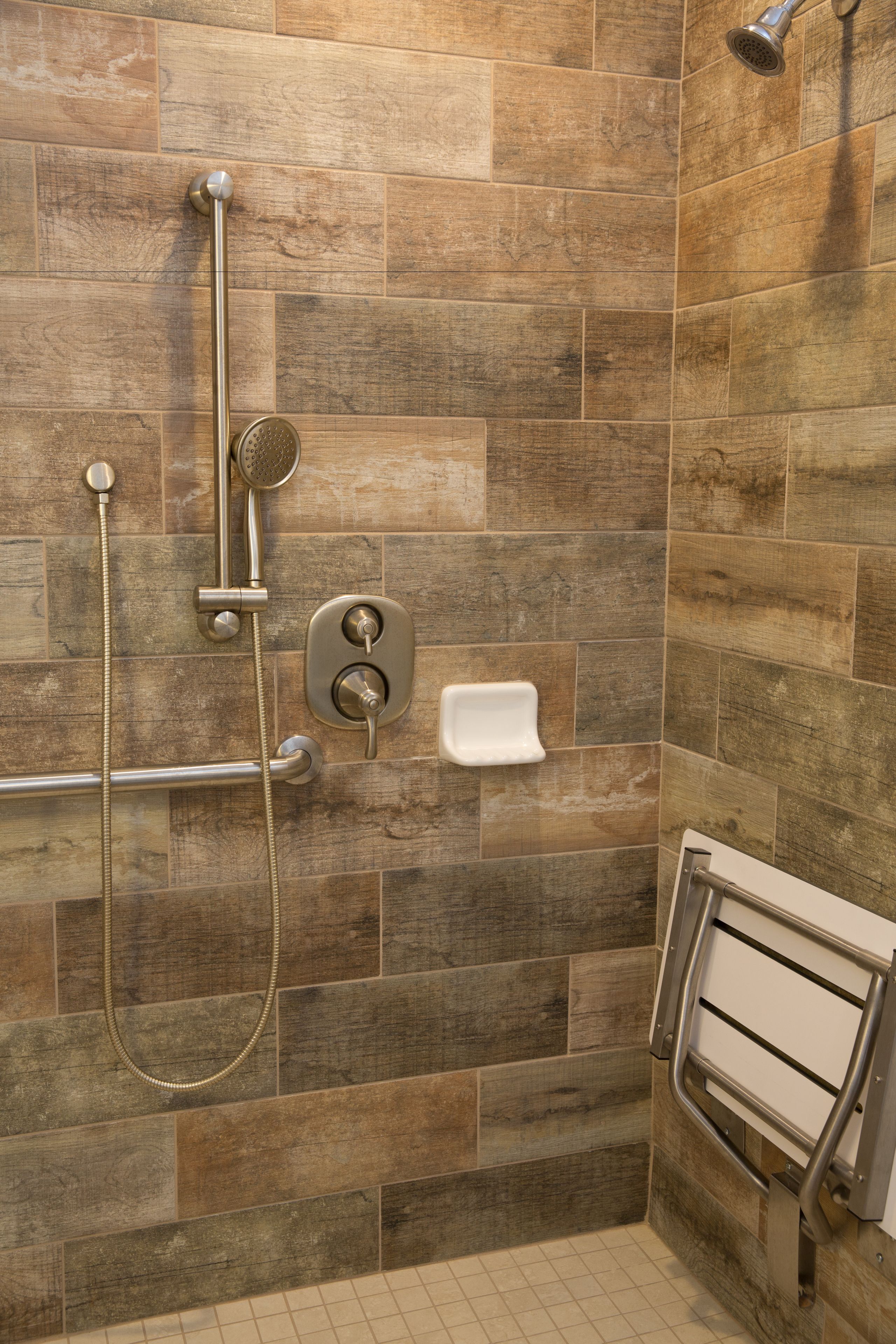 A shower area with a handheld showerhead, a wall-mounted control panel, and a handheld shower hose.