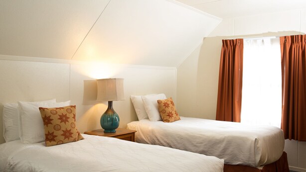 A hotel room with two beds, a lamp, and a window with curtains. - June Lake Villager (June Lake)