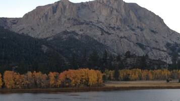 A mountainous landscape with a lake in the foreground and autumn-colored trees.