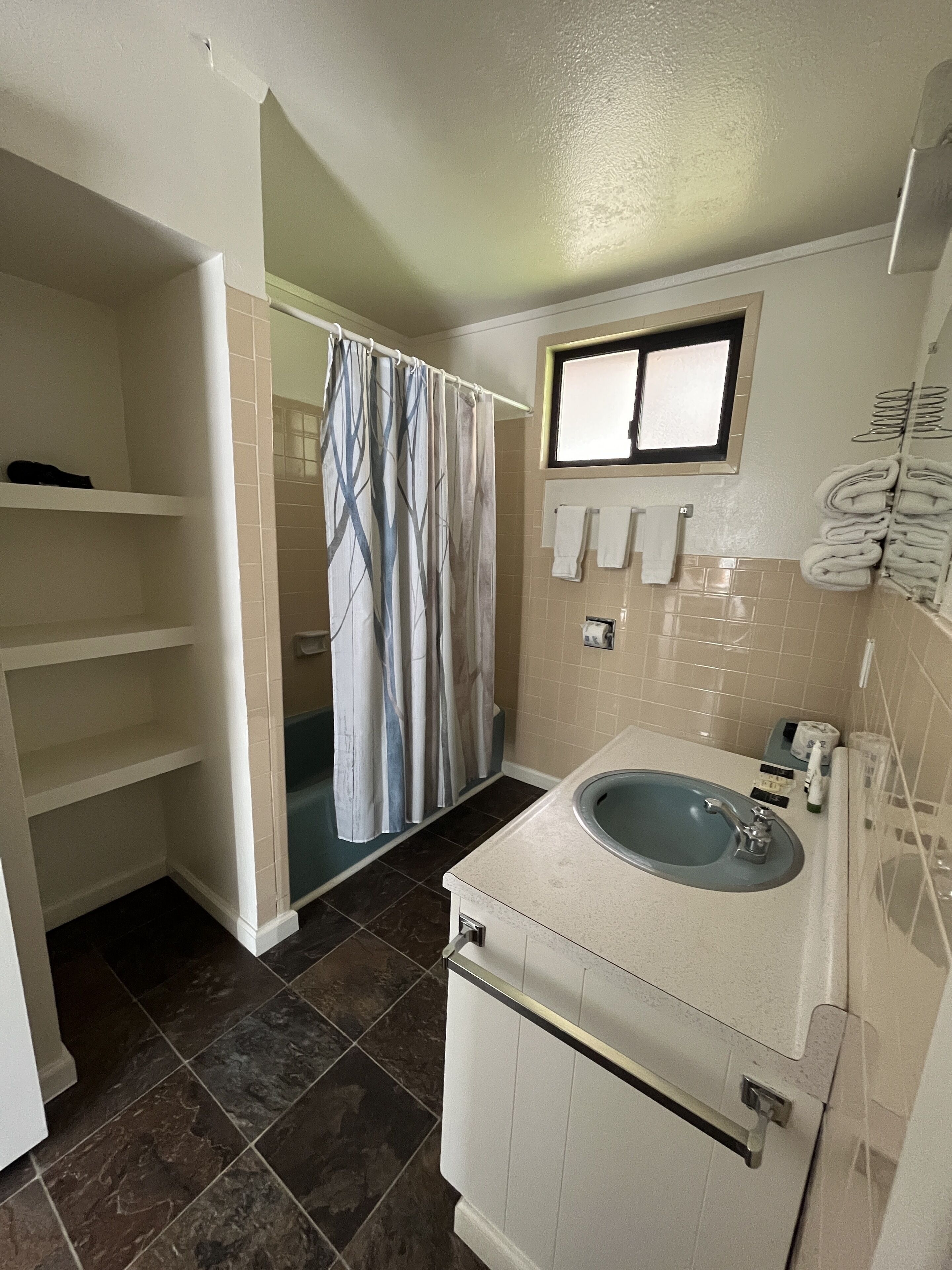 Un baño con bañera, lavamanos, ventana y toallero.