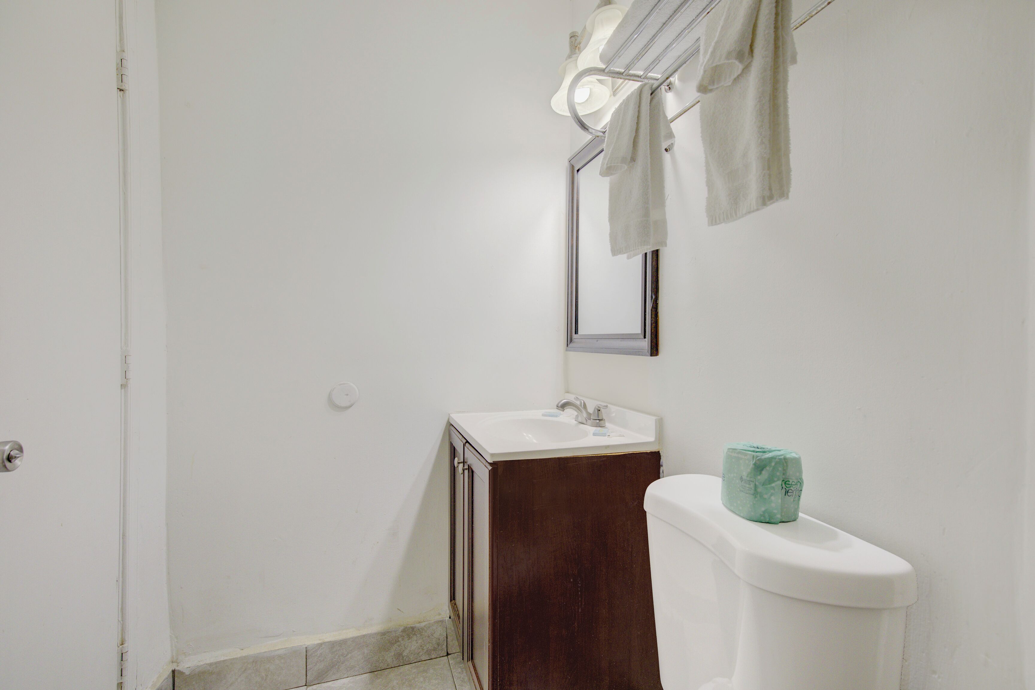 A small bathroom with a white sink, a mirror, and a toilet.