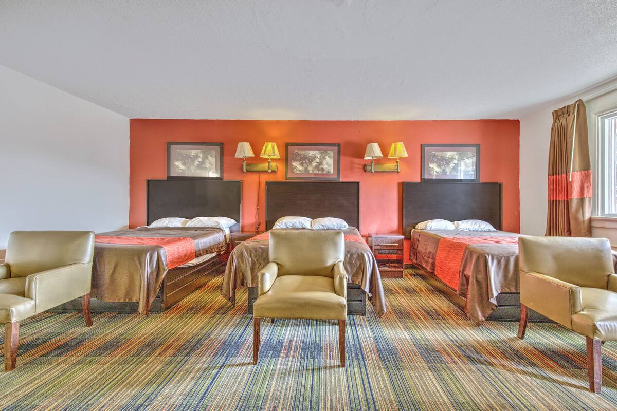 A hotel room with two beds, a sofa, a chair, and a carpeted floor.