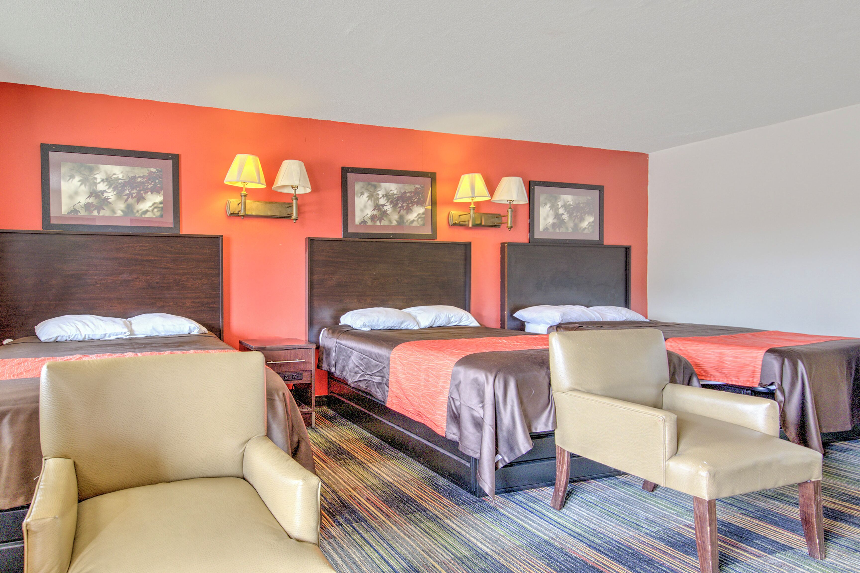 A hotel room with two beds, a sofa, a chair, and a carpeted floor.
