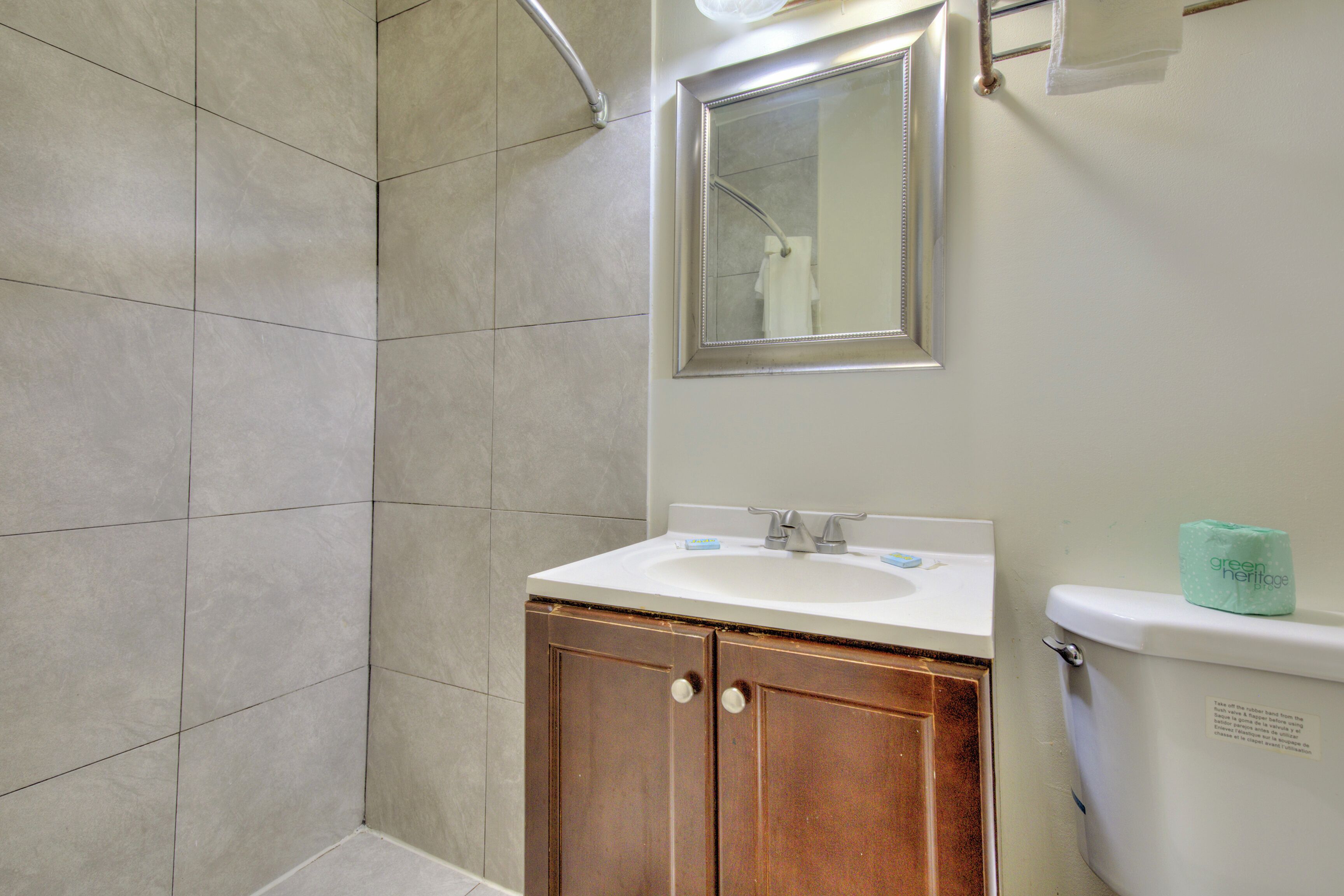 Un baño con lavamanos, espejo e inodoro.