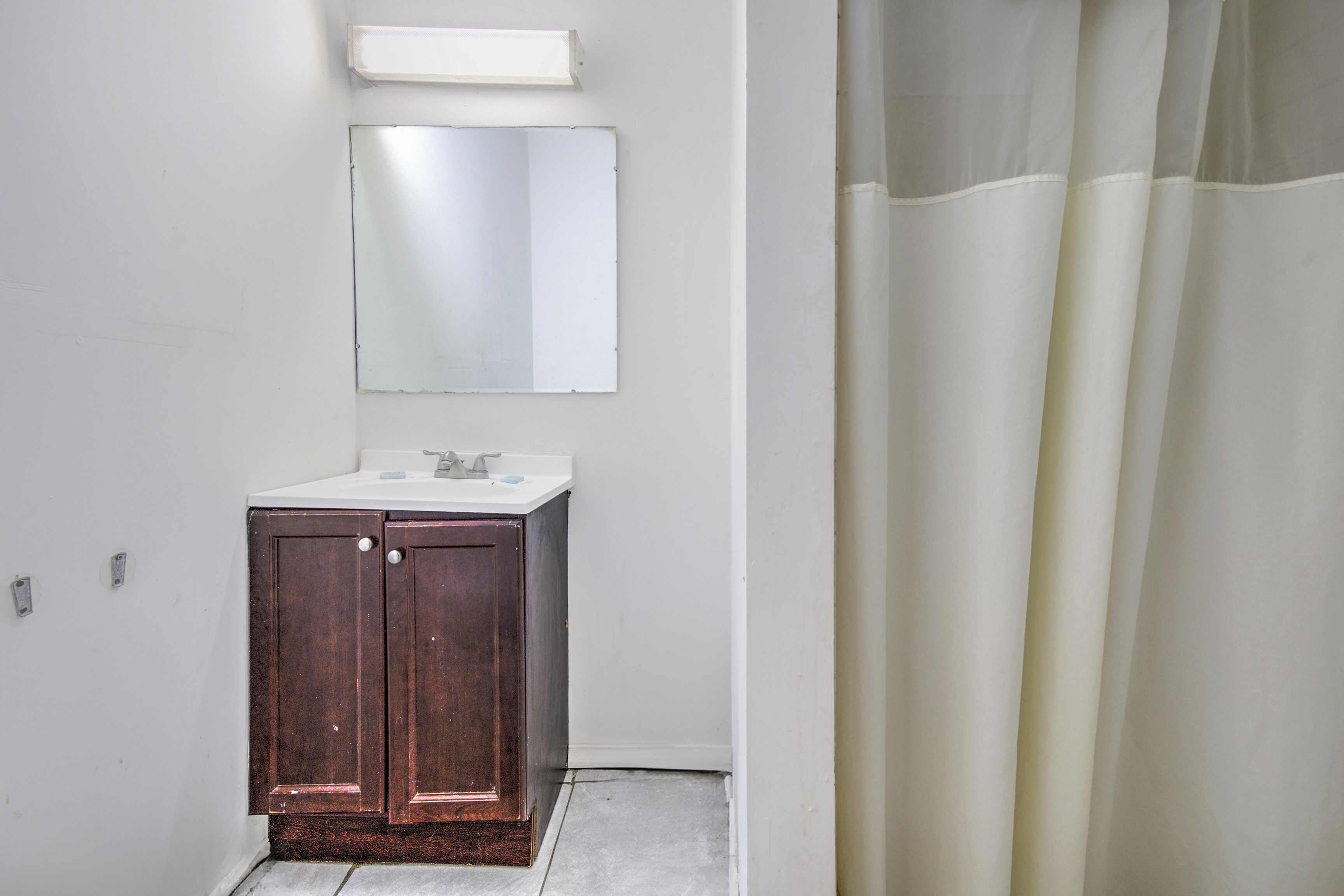 A bathroom with a white sink, a mirror above it, and a shower curtain.