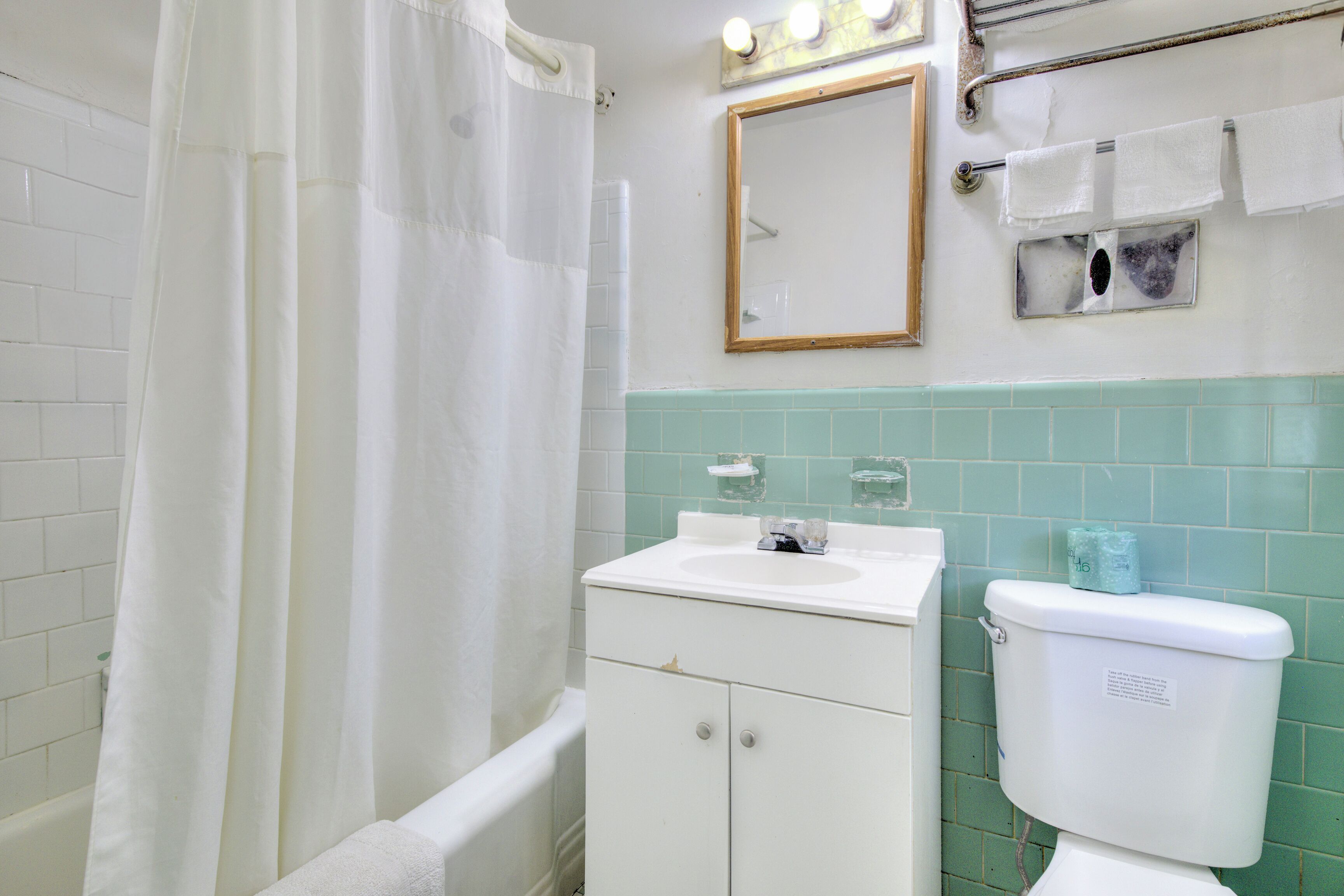 A bathroom with a white bathtub, a sink, a toilet, and a mirror.