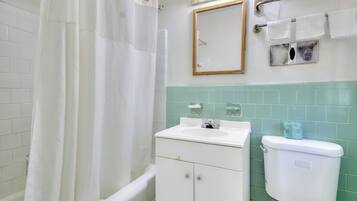 A bathroom with a white bathtub, a sink, a toilet, and a mirror.