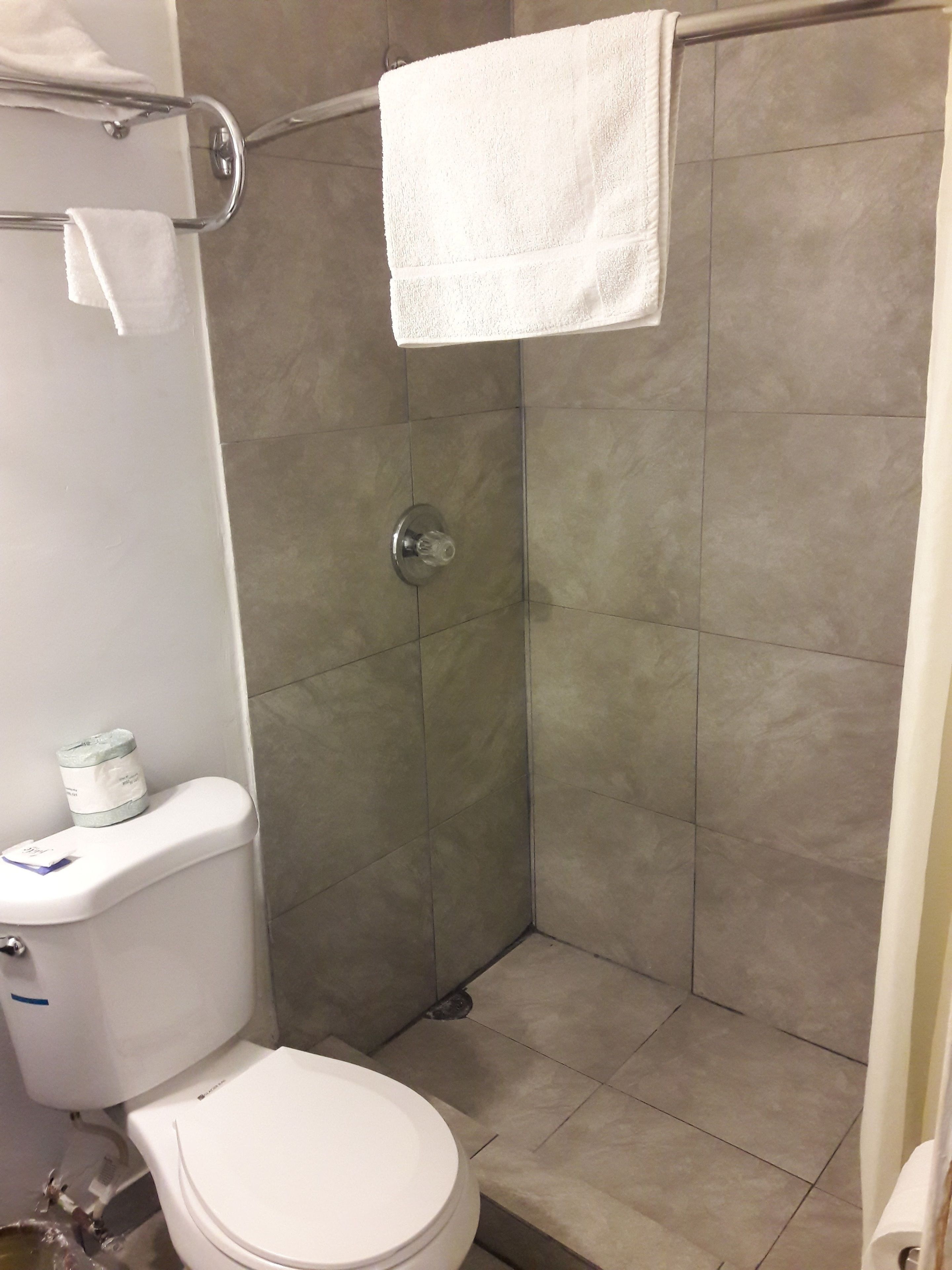 Un baño con inodoro, cabina de ducha y barra para toallas.