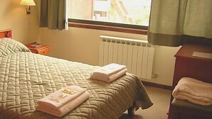 Une chambre d’hôtel avec un grand lit, une table de chevet, une commode et une fenêtre avec des rideaux.
