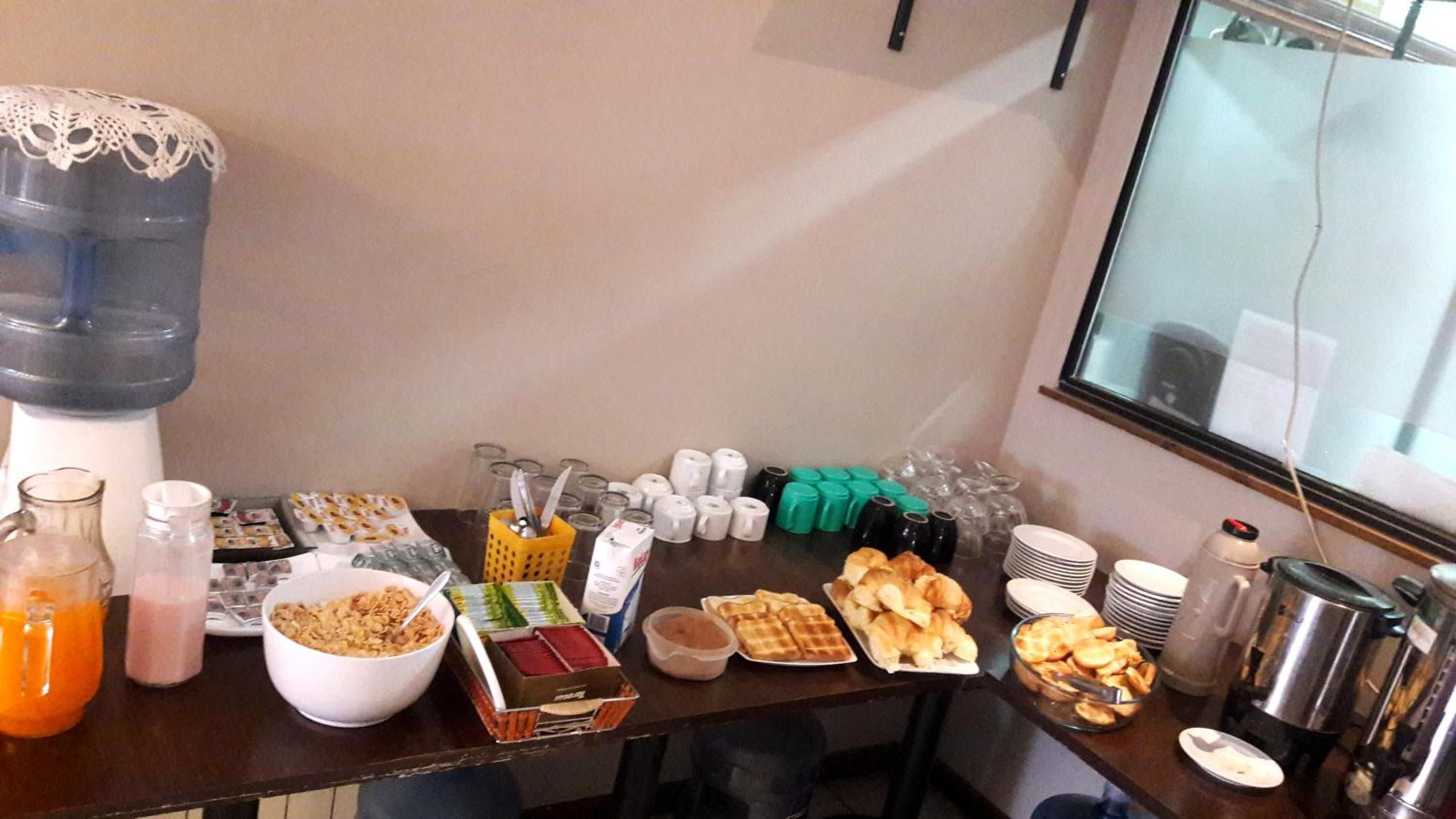 A buffet table with various food items, beverages, and utensils.