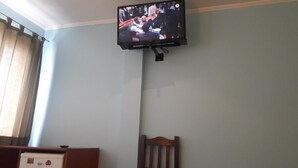 Un téléviseur fixé au mur dans une pièce dotée d’une fenêtre et d’un fauteuil.