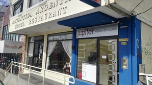 Un hôtel avec une enseigne indiquant « JUPITER AGENCIA DE CAMBIO » et un auvent bleu.
