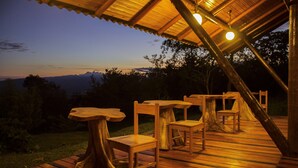 An outdoor wooden deck with tables and chairs, overlooking a scenic landscape. - Huasai Wasi Ecolodge (San Antonio de Cumbaza)