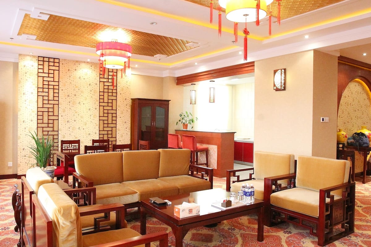 A traditional-style hotel lobby with a sofa, chairs, a coffee table, and a reception desk.