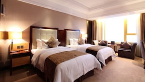 Een hotelkamer met twee bedden, een zithoek en een groot raam.