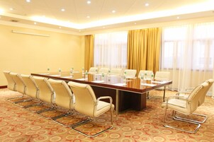 A conference room with a long table, six chairs, and a carpeted floor.