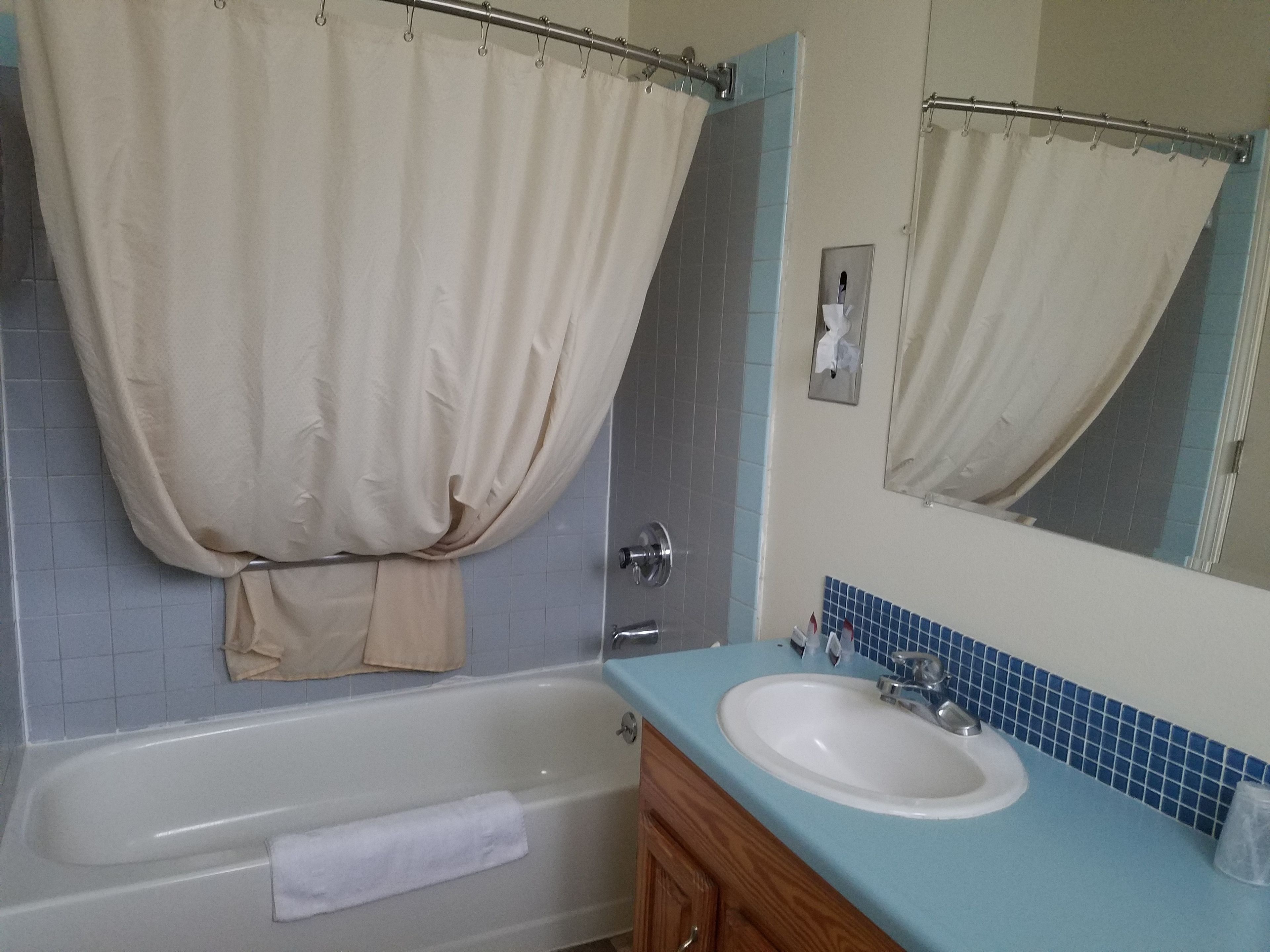 Un baño con bañera, lavamanos, espejo y perchero para toallas.