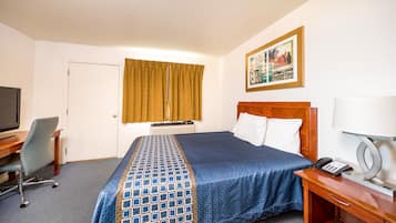 A hotel room with a bed, a desk with a chair, a television, a telephone, and a painting on the wall.