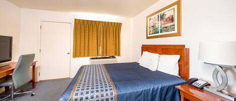 A hotel room with a bed, a desk with a chair, a television, a telephone, and a painting on the wall.
