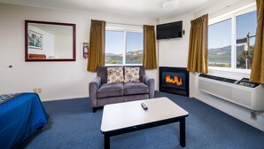 A room with a sofa, a table, a fireplace, and a TV.