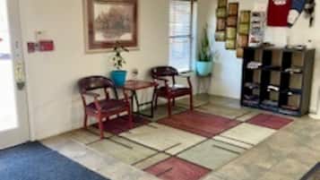 A reception area with a tiled floor, a reception desk, a framed picture on the wall, and a potted plant.